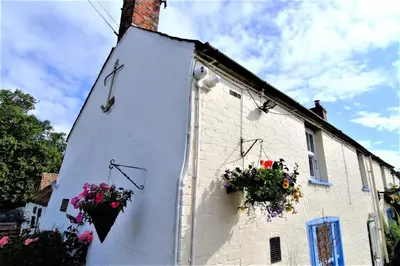 a clock on the side of a building with flowers on it at The Anchor in Sutton