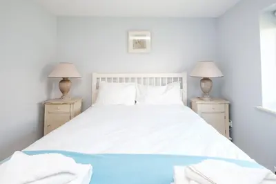 a bedroom with a white bed with two lamps at 201 High Street in Aldeburgh