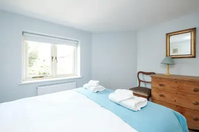 a bedroom with a bed and a dresser and a window at 201 High Street in Aldeburgh