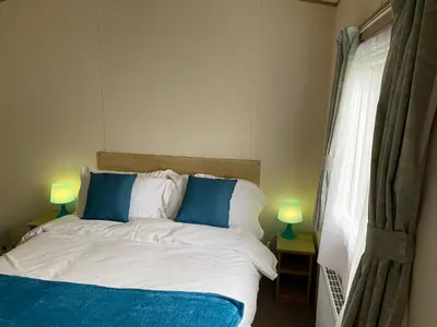 a bedroom with a bed with blue pillows and two lamps at 5 mins walk to beach. 3 bedroom caravan. Sleeps 8 in Clacton-on-Sea