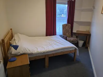 a bedroom with a bed and a chair and a window at HARLOW INTERNATIONAL HOSTEL in Harlow