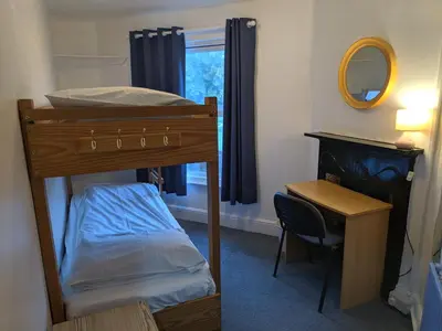 a bedroom with a bunk bed and a desk and a mirror at HARLOW INTERNATIONAL HOSTEL in Harlow