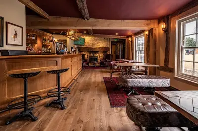 a bar in a pub with tables and chairs at Guinness Arms in Icklingham