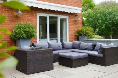 a wicker couch sitting outside of a brick house at Winton Lodge in Aldeburgh