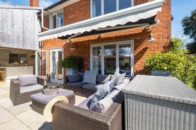 a patio with wicker furniture and a brick building at Winton Lodge in Aldeburgh