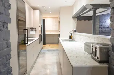 a kitchen with white cabinets and a stone wall at The Kings Head in Chelmsford