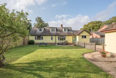 a yellow house with a yard with a fence at The Spinney Saxtead nr Framlingham in Woodbridge