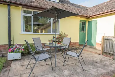 a table and chairs with an umbrella on a patio at The Spinney Saxtead nr Framlingham in Woodbridge