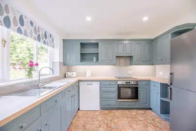 a kitchen with blue cabinets and a sink and a refrigerator at The Spinney Saxtead nr Framlingham in Woodbridge