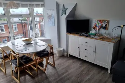 a living room with a dining room table and a television at 2 Bedroom Seafront Apartment in Felixstowe