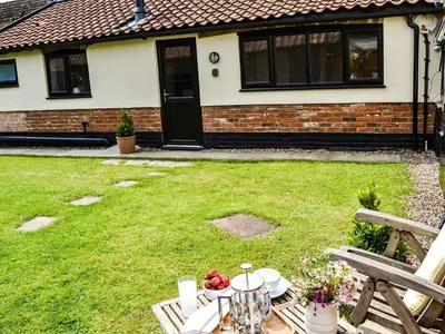 a garden with a table and a house at The Bothy in Hockham