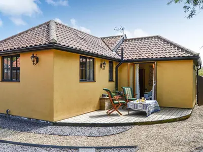 a yellow house with a table on a deck at Bradcar Farm Cottage in Snetterton