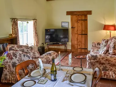 a living room with a table with a bottle of wine at Bradcar Farm Cottage in Snetterton