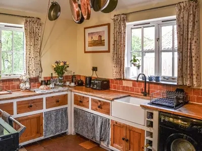 a kitchen with wooden cabinets and a sink at Bradcar Farm Cottage in Snetterton