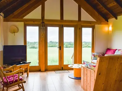 a living room with sliding glass doors and a television at The Long Barn in Chelmsford