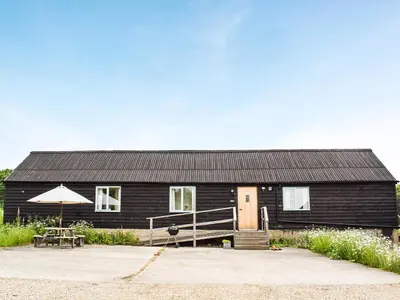 a black house with a table and an umbrella at The Long Barn in Chelmsford