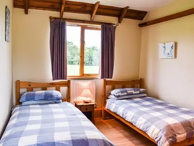 two beds in a room with a window at The Long Barn in Chelmsford