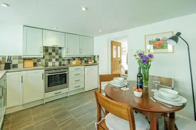 a kitchen with a wooden table and a dining room at Poppy Cottage, Aldeburgh - Prime location, close to the beach and High Street - Aldeburgh Coastal Cottages in Aldeburgh