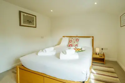 a bedroom with a large white bed with towels on it at Poppy Cottage, Aldeburgh - Prime location, close to the beach and High Street - Aldeburgh Coastal Cottages in Aldeburgh
