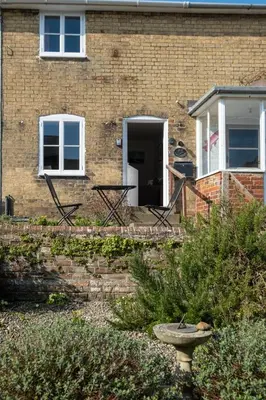 a brick house with a staircase leading to a door at Poppy Cottage, Aldeburgh - Prime location, close to the beach and High Street - Aldeburgh Coastal Cottages in Aldeburgh