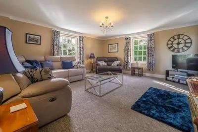 a living room with a couch and a tv at Maltings Lodge in Chelsworth