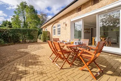 a patio with a wooden table and chairs at Maltings Lodge in Chelsworth