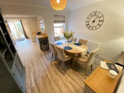 a dining room with a table and chairs and a clock at Refurbished Victorian Villa- Free Parking- Sleeps6 in Bury Saint Edmunds