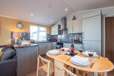 a kitchen with a wooden table with wine glasses on it at Chelsea Lodge - Aldeburgh Coastal Cottages in Sizewell