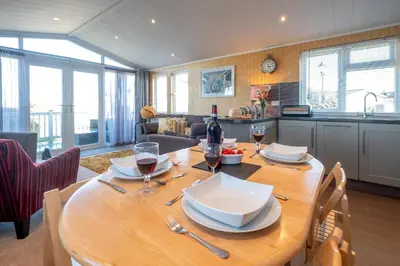 a kitchen with a wooden table with glasses of wine at Chelsea Lodge - Aldeburgh Coastal Cottages in Sizewell