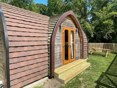 a small shed with a wooden door and a bench at Wildflower Meadow Cabins in Whitington