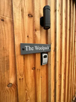 a wooden fence with a door with a sign on it at Wildflower Meadow Cabins in Whitington
