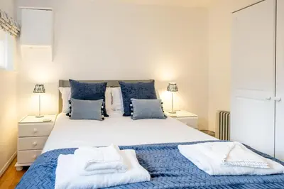 a bedroom with a large bed with blue sheets and pillows at The Britten - Aldeburgh Coastal Cottages in Aldeburgh