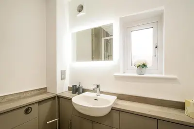 a bathroom with a sink and a mirror and a window at The Britten - Aldeburgh Coastal Cottages in Aldeburgh