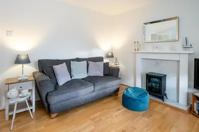 a living room with a couch and a fireplace at The Britten - Aldeburgh Coastal Cottages in Aldeburgh