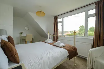 a bedroom with a bed and a large window at Kittiwake, Aldeburgh - Aldeburgh Coastal Cottages in Aldeburgh