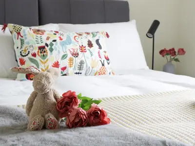 a teddy bear sitting on a bed with roses at Oak Cottage at Gravel Farm in Stretham