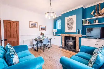 a blue living room with a blue couch and a table at 232a High Street, Aldeburgh in Aldeburgh