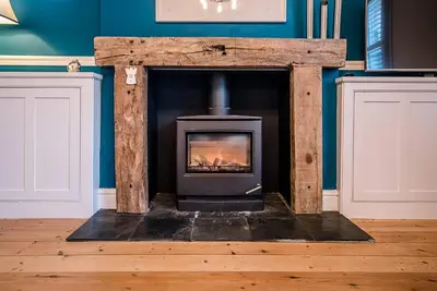 a woodburning stove in a room with a blue wall at 232a High Street, Aldeburgh in Aldeburgh