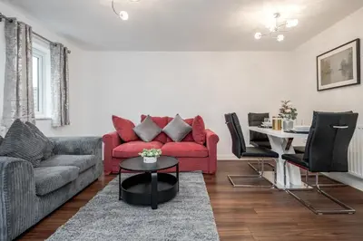 a living room with a red couch and a table at Stunning 3BR house in Basildon in Basildon