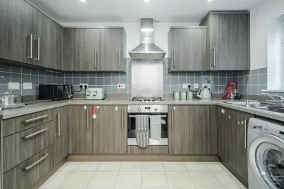 a kitchen with wooden cabinets and a stove top oven at Stunning 3BR house in Basildon in Basildon
