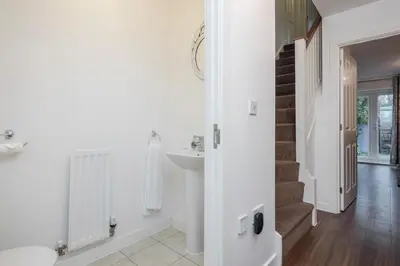 a white bathroom with a sink and a staircase at Stunning 3BR house in Basildon in Basildon