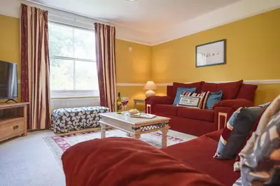 a living room with a red couch and a table at The Farmhouse Boundary Farm Framlingham in Woodbridge