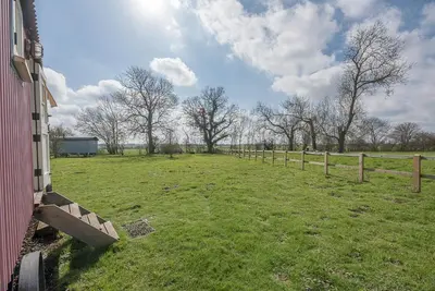 a field with a fence and trees in the background at Thyme Shepherds Hut Boundary Farm, Framlingham in Woodbridge