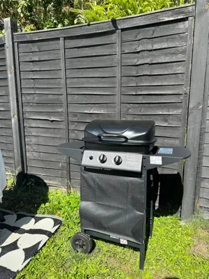 a grill sitting in the grass next to a fence at 2 Bedroom Garden Studio in Cambridge City Centre with Parking in Cambridge