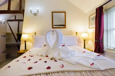two swans are sitting on a bed with hearts at Lavender Cottage in Thorndon