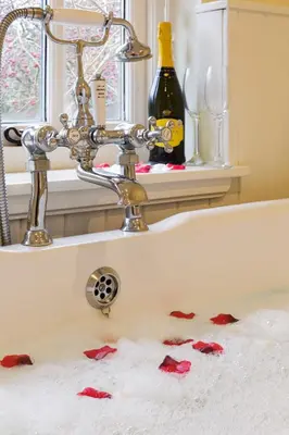a bathroom sink with red rose petals on the floor at Lavender Cottage in Thorndon
