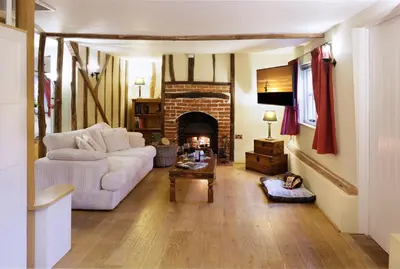 a living room with a white couch and a fireplace at Lavender Cottage in Thorndon