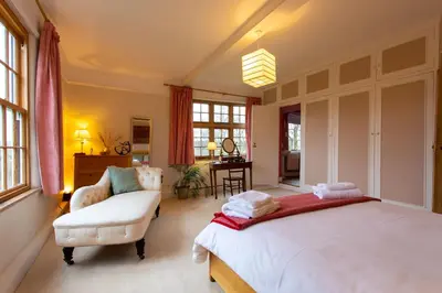 a bedroom with a large bed and a chair at Pounce Hall -Stunning historic home in rural Essex in Saffron Walden