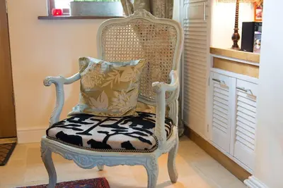 a white chair with a pillow on top of it at Meddlars a historic cottage on the countryside edge of a vibrant Market Town in Hadleigh