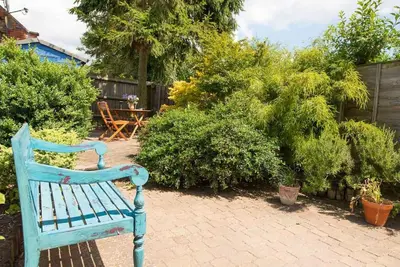 a blue bench sitting on a brick patio at Meddlars a historic cottage on the countryside edge of a vibrant Market Town in Hadleigh